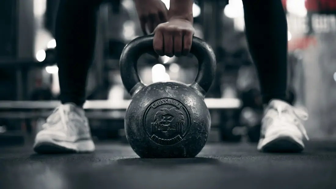 A hand gripping a kettlebell in a gym