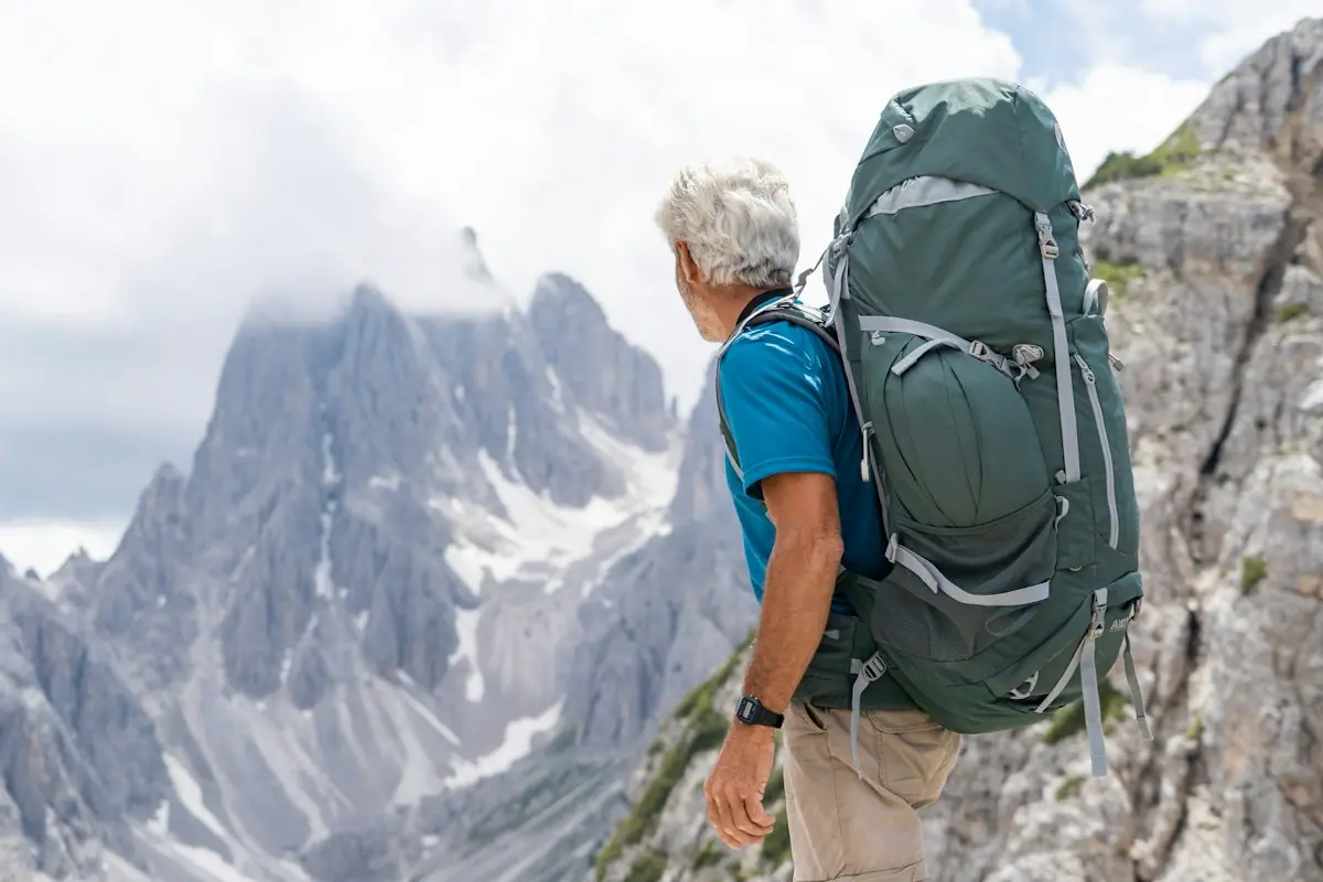 A grey-haired hiker looking out at mountain peaks